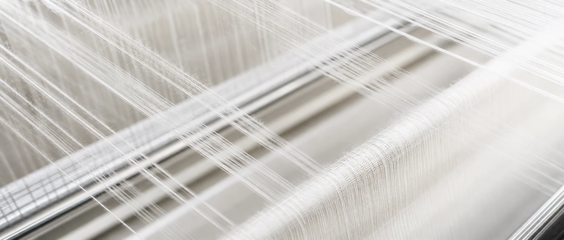 Fine textile fibers crossing a precision weaving loom